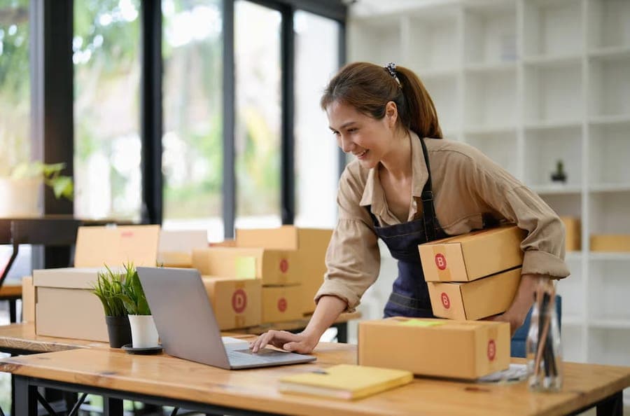 Bakery owner packing orders beside her laptop